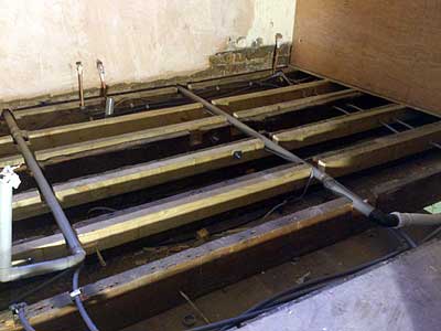 Two rows of pipes sitting in large notches cut into the upper half of the joists